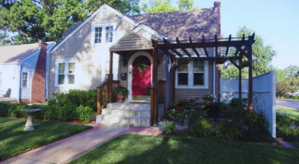small home with pergola by porch and green grass
