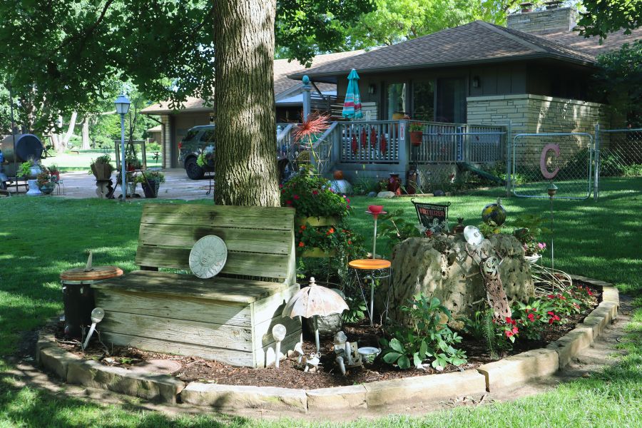 Wood bench under tree surrounded by garden decor