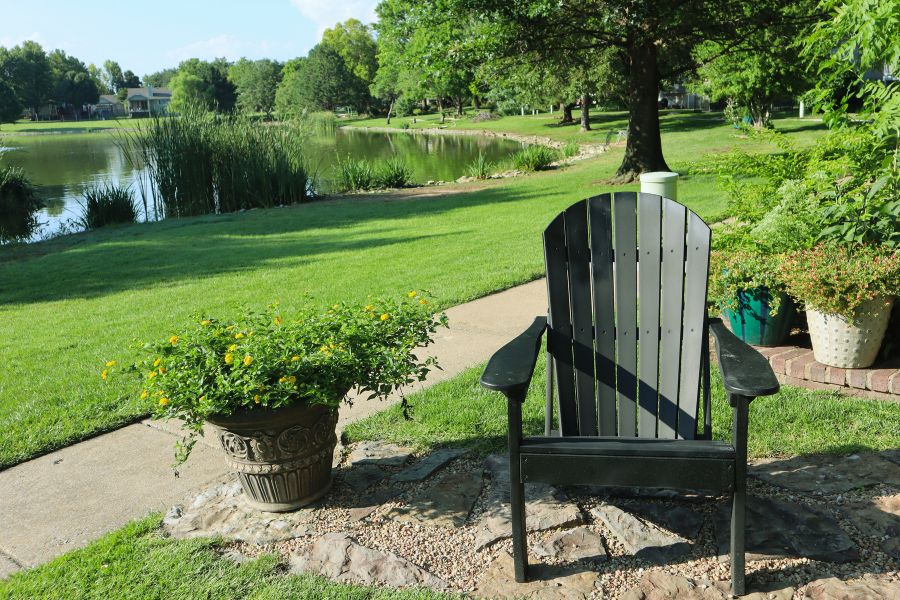 lawn chair next to a colorful pot overlook a community pond