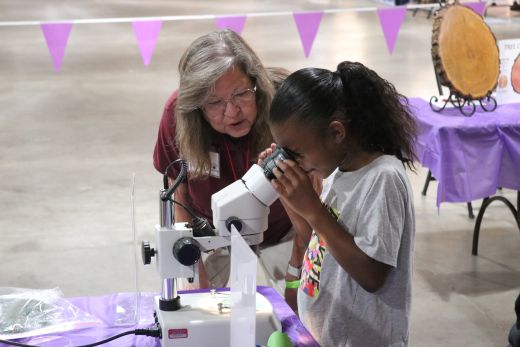 Linda Self, an Extension Master Gardener in Sedgwick County since 2023, assists a participant in looking at tree samples through a microscope during a portion of the award-winning program, How Trees Drink, Breathe and Grow.