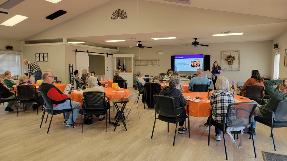 Photo of nutrition class with presentation on the screen and people around watching the slides. 